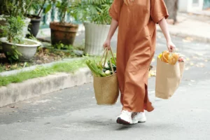Femme portant de lourds sacs de courses, illustrant le transfert de la force dans la vie de tous les jours - Fitspro Equipement .