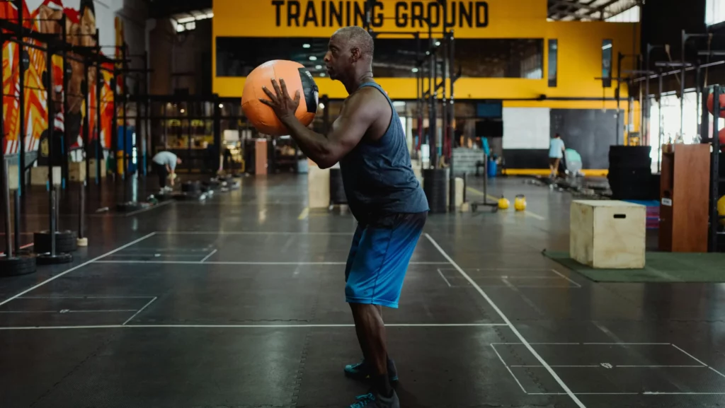 Homme effectuant un exercice de squat avec un medicine ball dans une zone d'entraînement fonctionnel - Fitspro Equipement