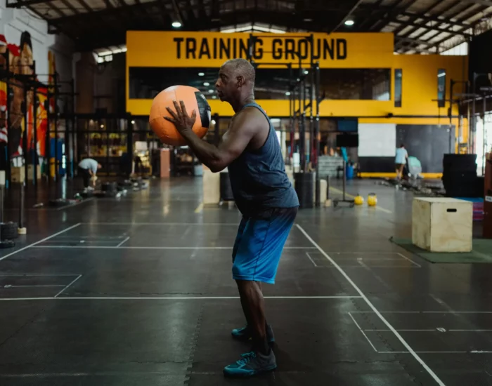 Homme effectuant un exercice de squat avec un medicine ball dans une zone d'entraînement fonctionnel - Fitspro Equipement