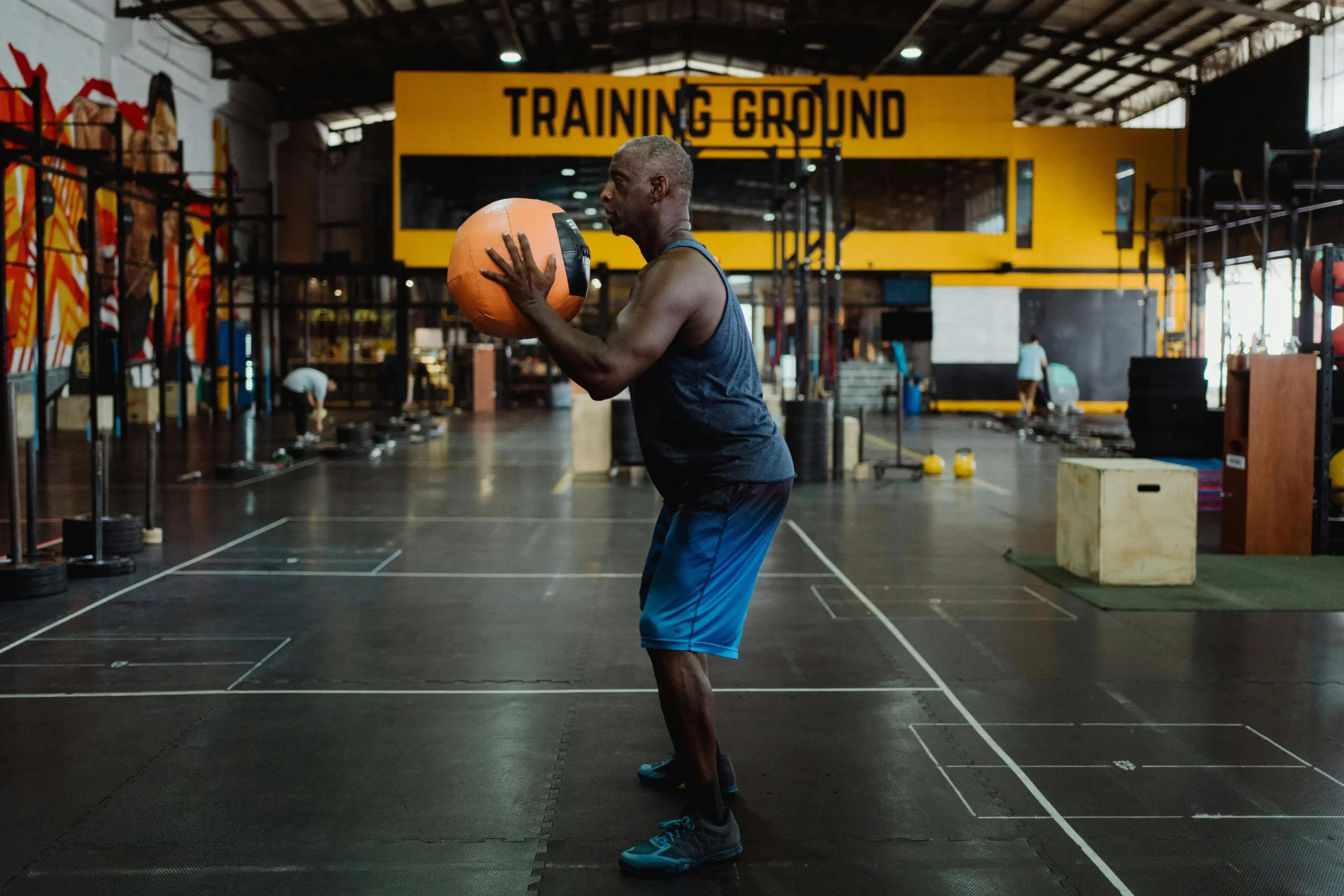 Homme effectuant un exercice de squat avec un medicine ball dans une zone d'entraînement fonctionnel - Fitspro Equipement