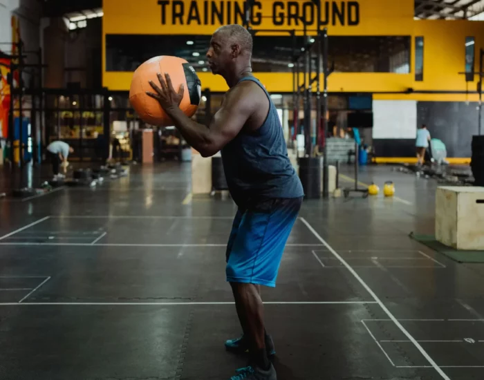 Homme réalisant un squat avec un medecine ball dans une salle d'entraînement fonctionnel.