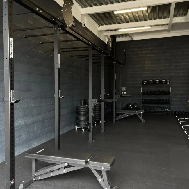 Installation d'une cage de cross-training et de racks de musculation de la marque KingsBox dans une salle de sport moderne.