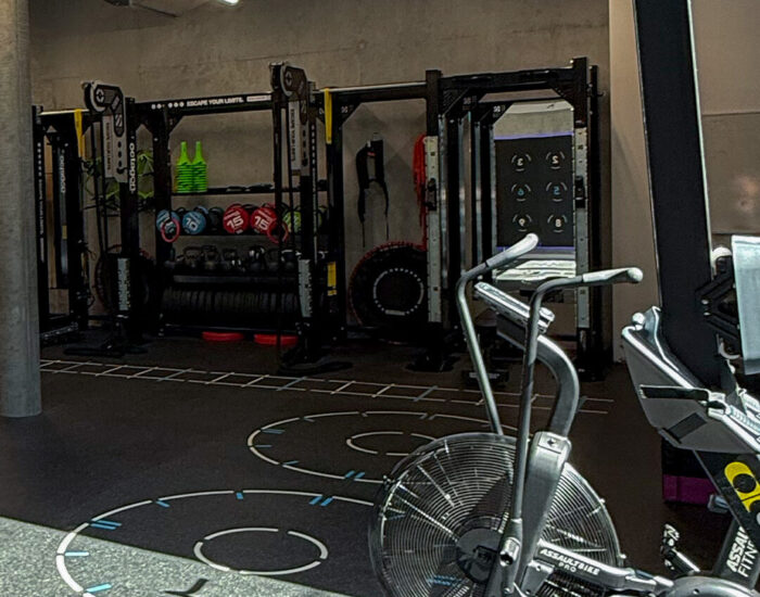 Zone de cross-training équipée d'un Assault AirBike, d'une cage de musculation avec kettlebells et d'un marquage au sol pour l'entraînement fonctionnel - Fitspro Equipement