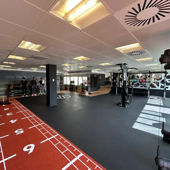 Vue d'un espace d'entraînement fonctionnel comprenant une piste de sprint rouge - Fitspro Equipement
