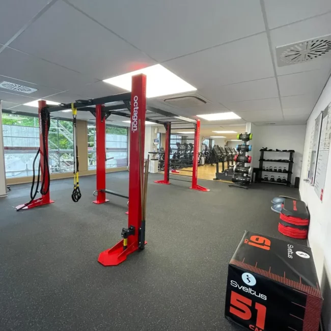 Espace de cross-training avec portique Octagon rouge, sangles de suspension, box de pliométrie Sveltus et accessoires de musculation.